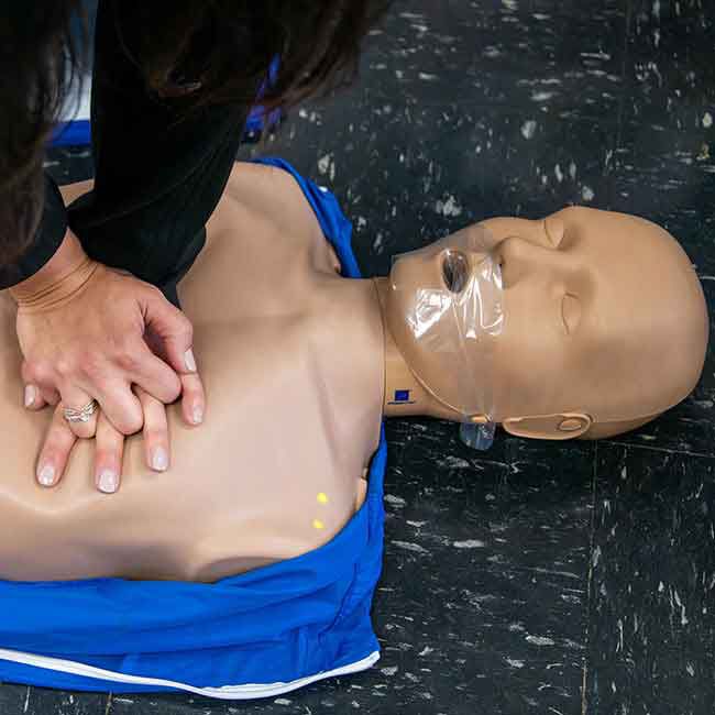 Student practicing CPR compressions on a Prestan Adult Manikin.