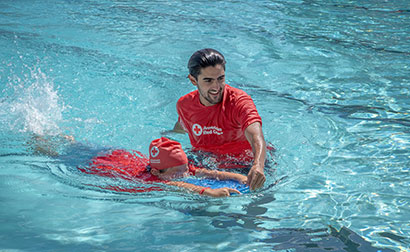 A Red Cross Swimming Instructor teaching a student swimming techniques.