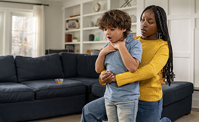 Babysitter performing abdominal thrusts on a choking child.