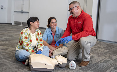 CPR training session with an American Red Cross Instructor and two participants practicing on a CPR manikin.
