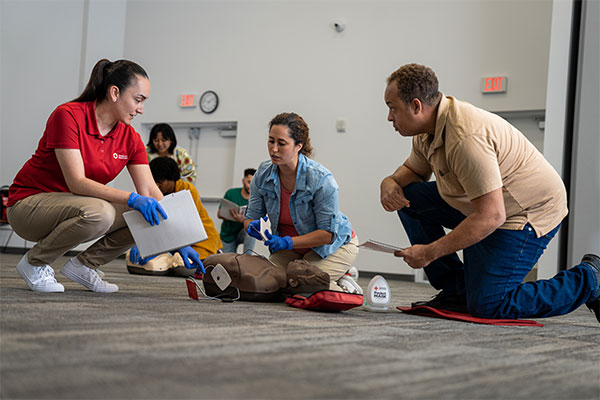 A Red Cross instructor in New York explains to students how to place an AED’s adhesive pads on a manikin.