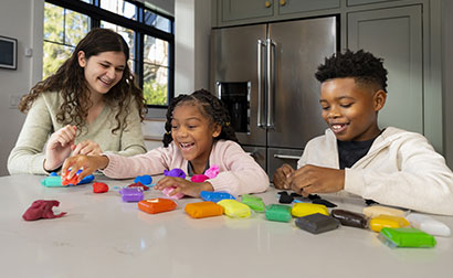 Babysitter and children playing with modeling clay.