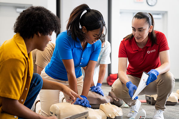 A woman practices performing CPR in Irvine, California while another student watches and the instructor monitors.
