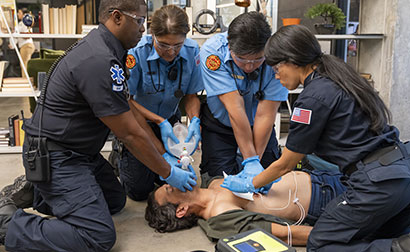 EMS team performing CPR and using an AED and bag valve mask on an unconscious person.