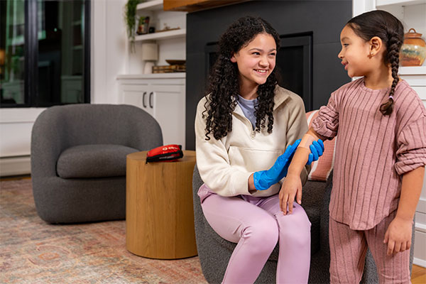 A babysitter in Michigan bandages a child's arm using a Red Cross First Aid Kit.